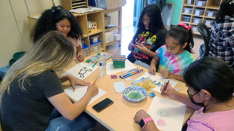 Indoor photo children doing arts and crafts at a classroom table
